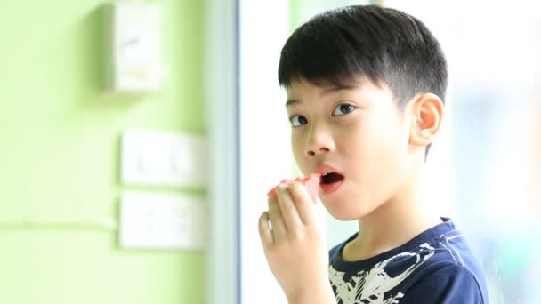 Pieni aasialainen söpö poika syö kypsä vesimeloni — kuvapankkivideo