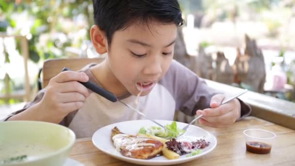 Pequeño niño asiático comiendo el almuerzo en casa — Vídeo de stock