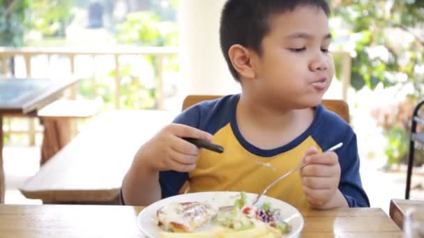 Pequeño niño asiático comiendo el almuerzo en casa — Vídeo de stock