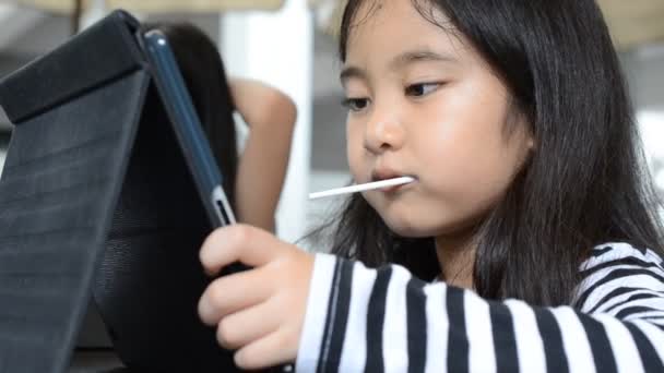 Petite fille asiatique jouant tablette sur la table — Video