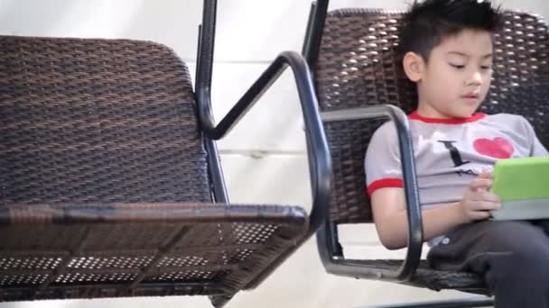 Азиатский милый мальчик играет планшетный компьютер в парке в яркий летний день — стоковое видео