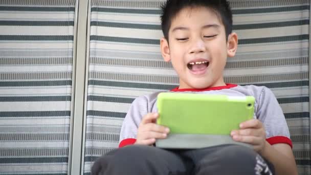 Asiático lindo chico jugando tableta pc en el parque en brillante día de verano — Vídeos de Stock