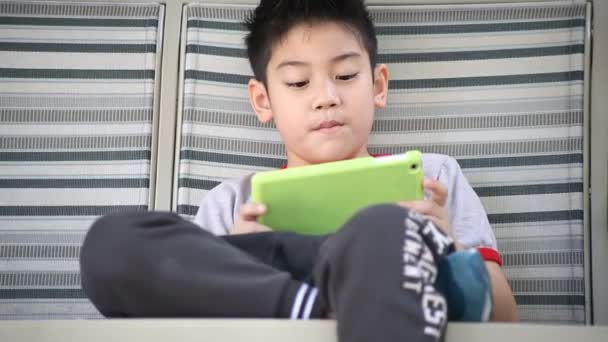Asiático lindo chico jugando tableta pc en el parque en brillante día de verano — Vídeo de stock
