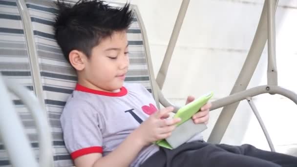 Ásia bonito menino jogar tablet pc no o parque no brilhante verão dia — Vídeo de Stock