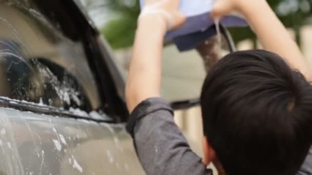 Aziatische schattige jongen wassen auto. Kind helpen schoon grote gezinsauto. — Stockvideo