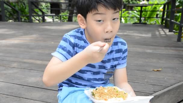 Jonge Aziatische schattige jongen eten van gebakken chiness noedels., in schuim vak — Stockvideo