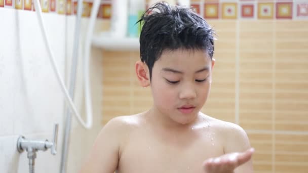 Liten asiatisk pojke använder fuktkräm i badrummet efter att ha en dusch — Stockvideo
