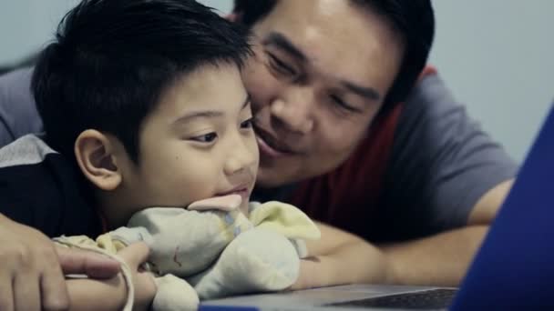 Šťastná rodina otce a syna, při pohledu na notebook na posteli v ložnici — Stock video