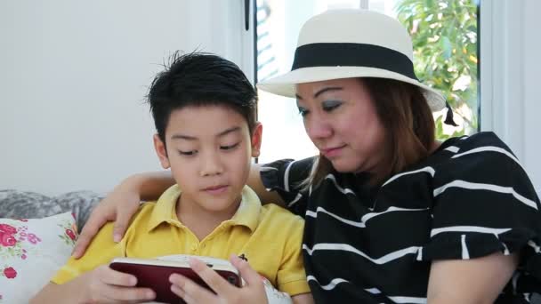 Happy asian boy and his mom playing games on smart phone — Stock Video