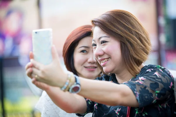 Happy asian woman with friend taking a selfie — Stock Photo, Image