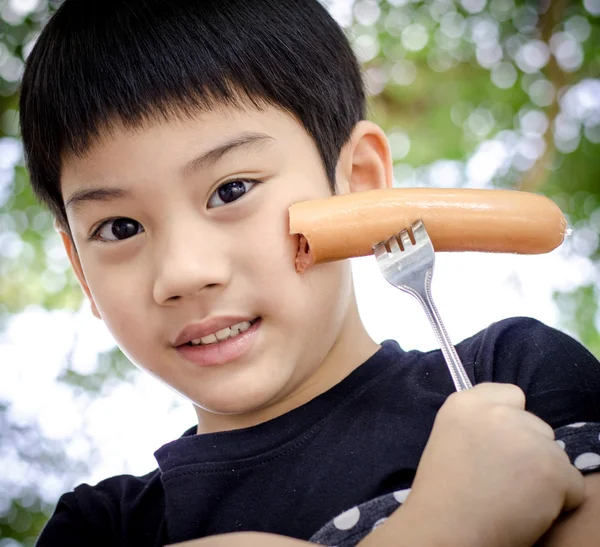 Enfant mangeant une saucisse — Photo