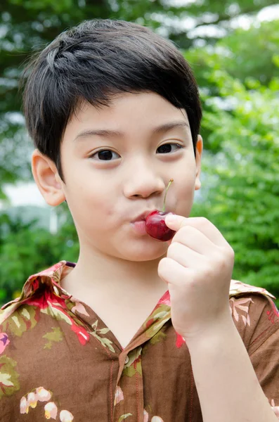 Aziatische jongen met een kers — Stockfoto