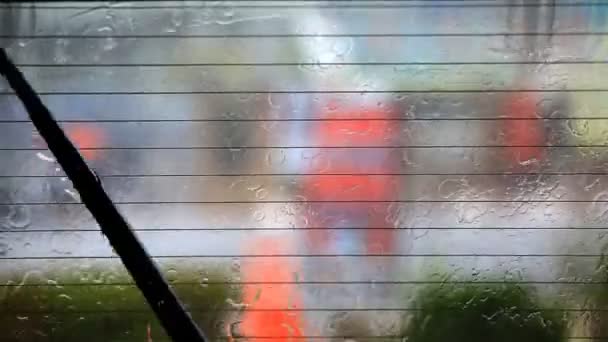 Imagen de gotas de lluvia cayendo sobre una ventana de coche con limpiaparabrisas haciendo — Vídeos de Stock