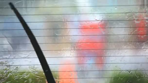 Imagen de gotas de lluvia cayendo sobre una ventana de coche con limpiaparabrisas haciendo — Vídeos de Stock