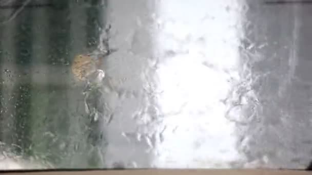 Εικόνα της βροχής πέφτει που υπάγονται σε ένα παράθυρο του αυτοκινήτου με υαλοκαθαριστήρα αυτοκινήτου κάνει — Αρχείο Βίντεο