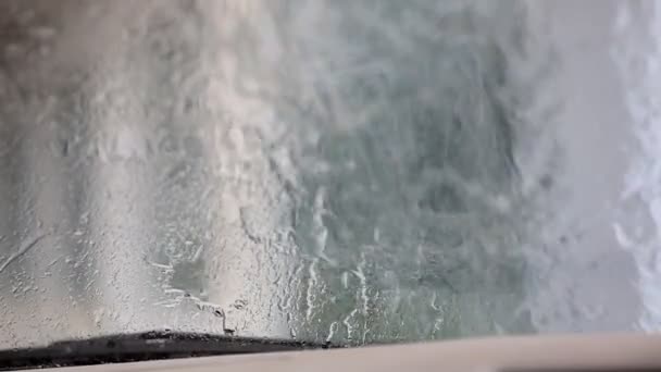 Imagen de gotas de lluvia cayendo sobre una ventana de coche con limpiaparabrisas haciendo — Vídeos de Stock