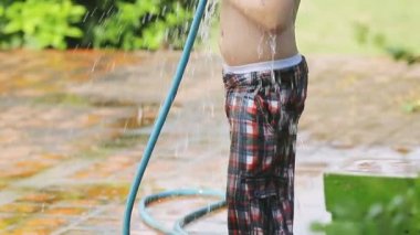 Mutlu Asyalı çocuk oynamak kauçuk tüp su ile sıcak yaz sıçramasına