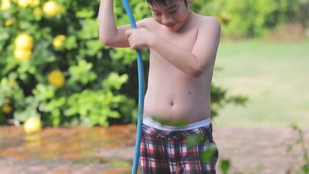 Happy asian child play splashing with rubber tube water on hot summer — Stock Video