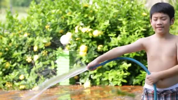 Gelukkig Aziatische kind spelen spatten met rubberen buis water op hete zomer — Stockvideo