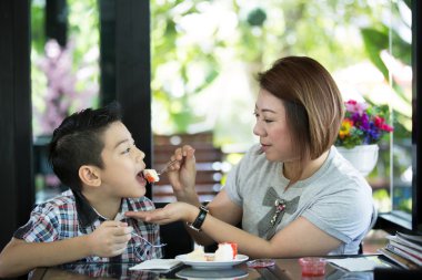 Asian Cute mom is feeding son with cake 
