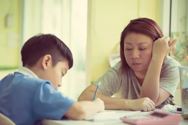 Serious Asian Mother Helping Son With Homework 