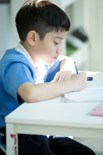 Giovane asiatico ragazzo doing suo homework — Foto Stock