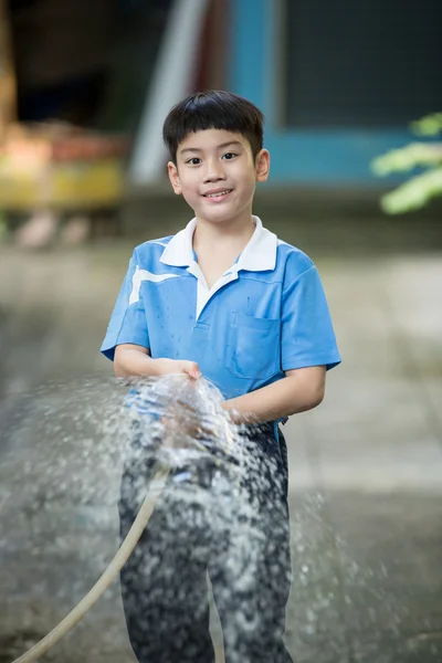 Happy Asian children  playing with water hose — Stockfoto