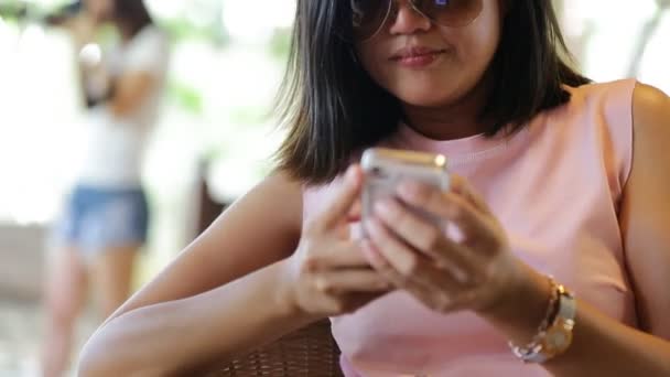 Mujer asiática utilizando la aplicación en el teléfono inteligente en la cafetería sonriendo y mensajes de texto en el móvil — Vídeo de stock