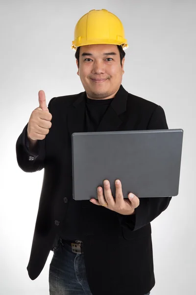 Portrait of asian smiling holding laptop with safety helmet — Stockfoto