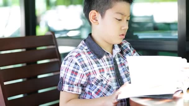 Asiático menino leitura livro em casa — Vídeo de Stock