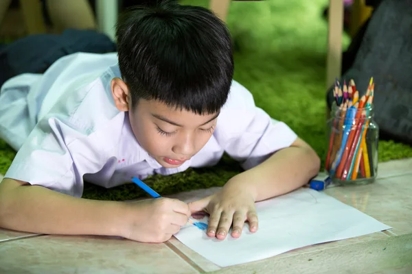 Asian child in student uniform painting on a white paper — Stock Photo, Image