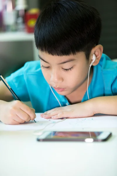 Asiatique garçon à l'aide de téléphone cellulaire et la peinture sur un papier blanc — Photo