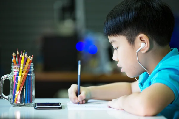 Menino asiático usando celular e pintura em um livro branco — Fotografia de Stock