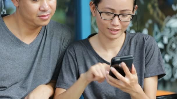 Feliz asiático hombre con chica amigo usando celular juntos son selfy — Vídeo de stock