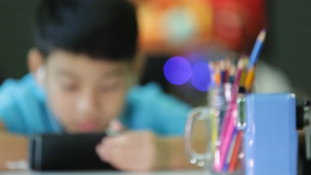 Dziecko azjatyckie za pomocą cyfrowego tabletu z ucho pąki na jego telefon komórkowy. — Wideo stockowe