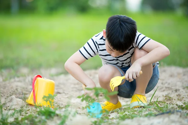 Roztomilý chlapec asijské hraní s hračkami v zahradě — Stock fotografie