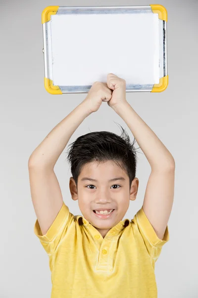 Aziatisch jongen is kleine glimlach met leeg wit bord en zoek cam — Stockfoto