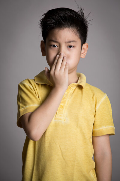 Young asian boy with both hands closing mouth