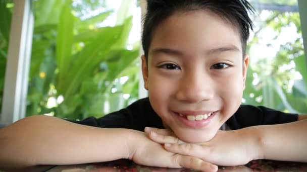 Niño asiático feliz expresión facial sobre fondo de hoja verde. joven con dos dientes perdidos . — Vídeo de stock