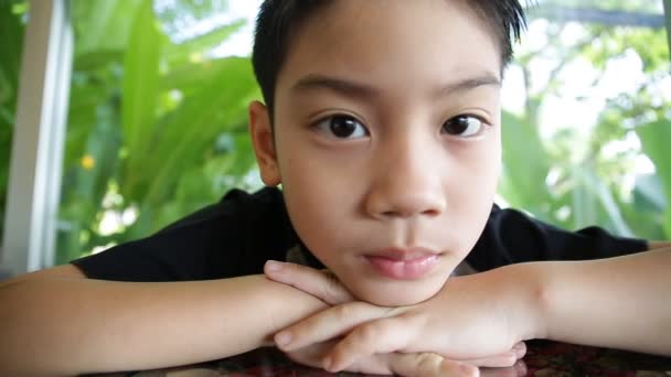 Asiatiska små barn glada ansiktsuttryck på grönt blad bakgrund. ung pojke med två saknade tanden. — Stockvideo