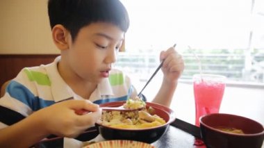 Mutlu asyalı çocuk japon öğle yemeği seti yemek ve kamera arıyor .