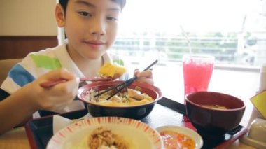 Mutlu asyalı çocuk japon öğle yemeği seti yemek ve kamera arıyor .