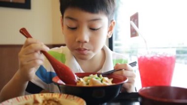Mutlu asyalı çocuk japon öğle yemeği seti yemek ve kamera arıyor .