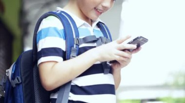 Asyalı çocuk dijital cep telefonu kullanma sırt çantası ile