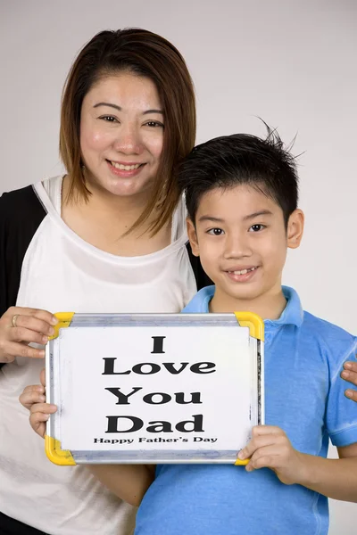 Asiático mãe e filho com placa branca em branco e olhando câmera — Fotografia de Stock