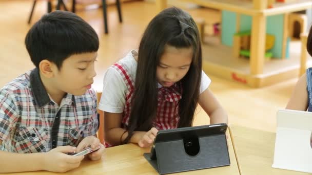コンピュータタブレットと一緒に遊ぶ小さなアジアの子供のグループ . — ストック動画
