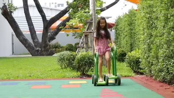 Pouco asiático menina equitação rápido um empurrar Carting / carrinho no playground / parque — Vídeo de Stock