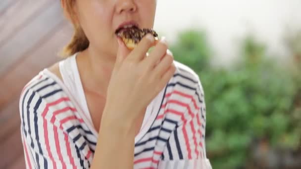 Boldog ázsiai nő élvezni étkezési édes ételek fánk — Stock videók