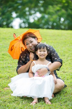 Küçük Asyalı kız annesi ile yeşil çimenlerin üzerinde oynama 