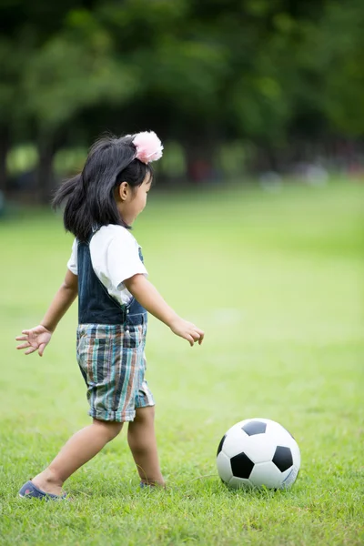 Piccola ragazza asiatica che gioca a calcio al parco — Foto Stock